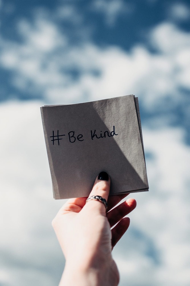 hand holding note that says be kind